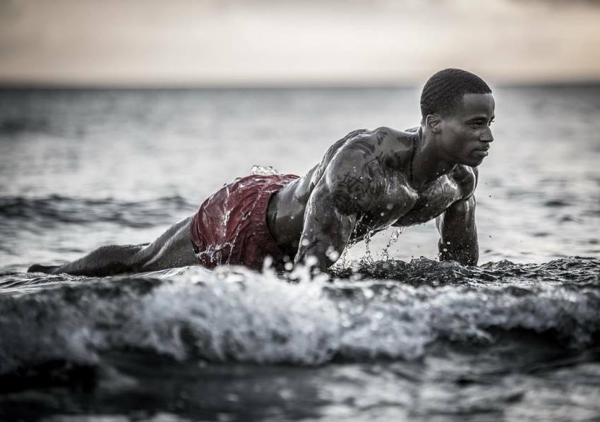 Andre Smith doing push ups on the shore, water splashing all over his ripped body