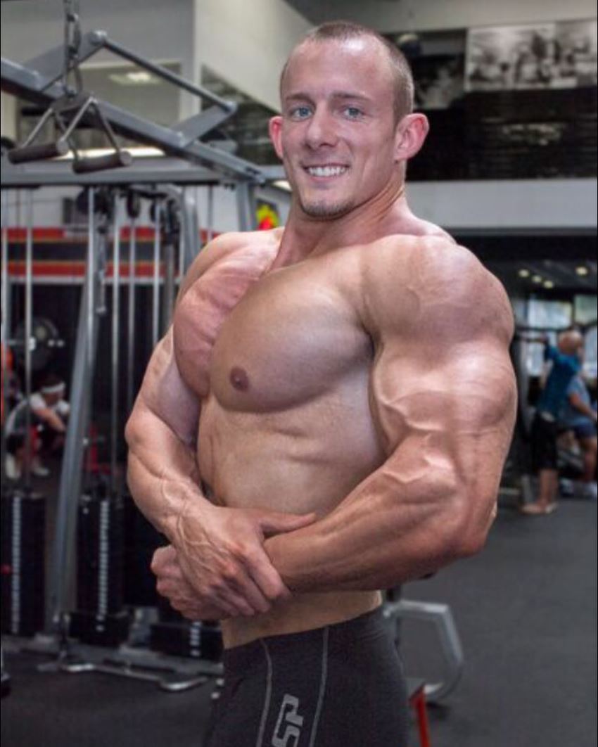 Brandon Gerdes doing a shirtless side chest pose in the gym