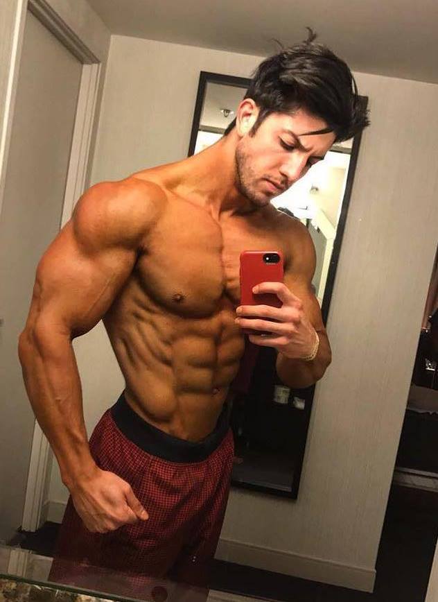 Jonny Bernstein taking a selfie of his flexed and ripped muscles in the mirror