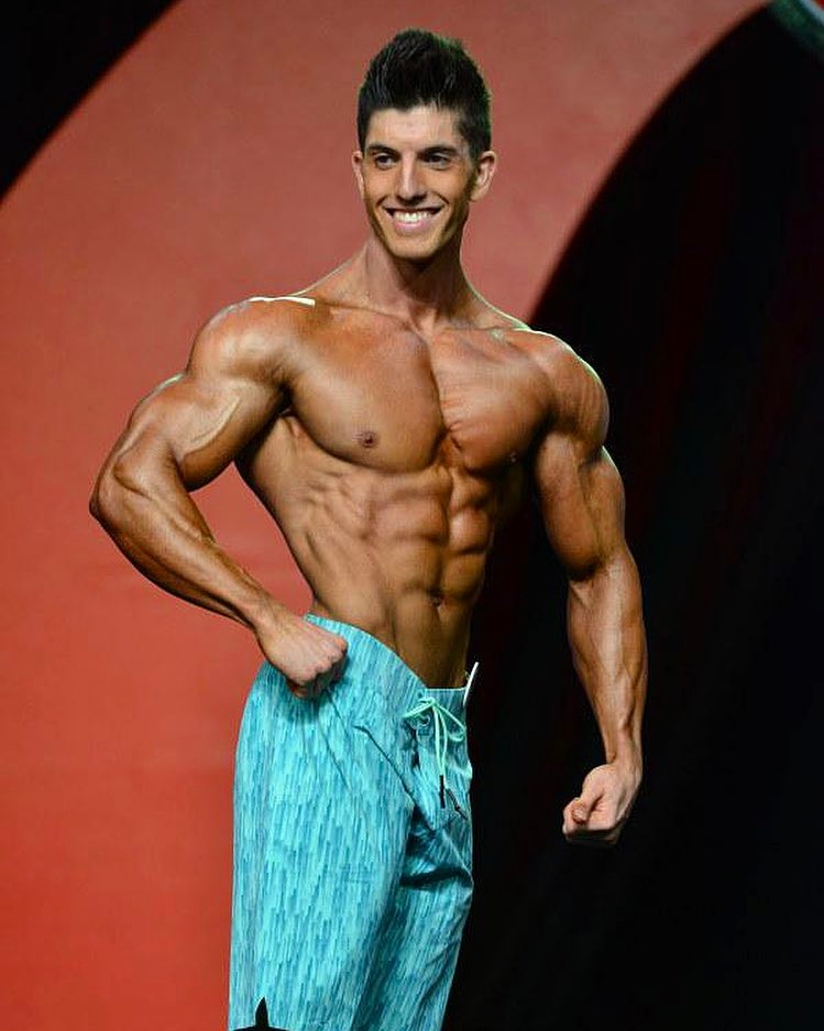 Jonny Bernstein on the Olympia stage in 2015, smiling at the judges and showing his conditioned physique