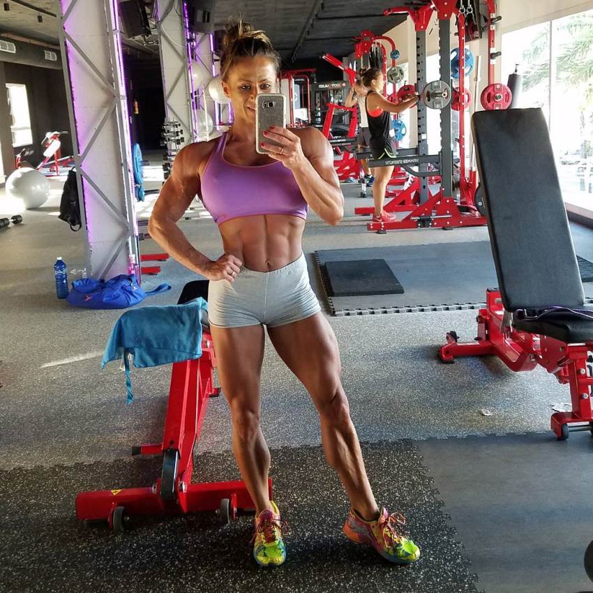 Maria Garcia taking a selfie of her lean abs, legs, and calves in the gym