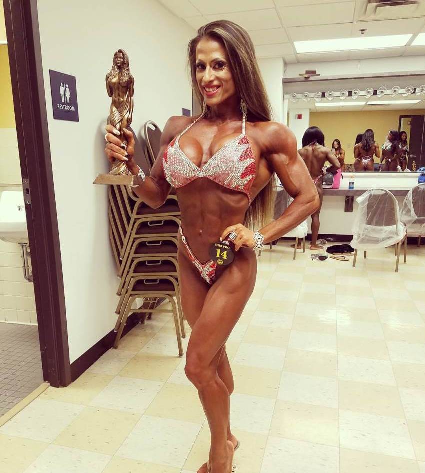 Maria Garcia posing for a photo with a statue trophy in her hand, smiling, and looking awesome