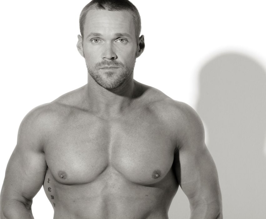 Chris Powell posing shirtless for a photo, looing lean and fit