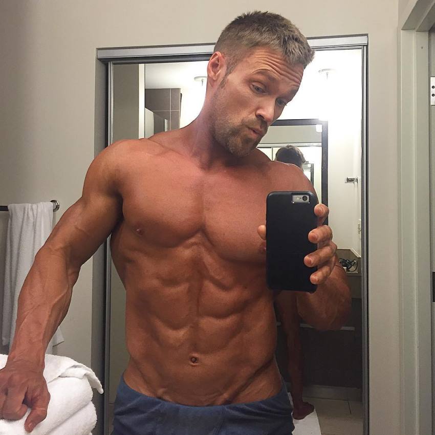 Chris Powell taking a bathroom selfie, his abs looking ripped