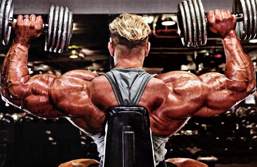 Dennis Wolf doing shoulder press with his enormous shoulders and arms