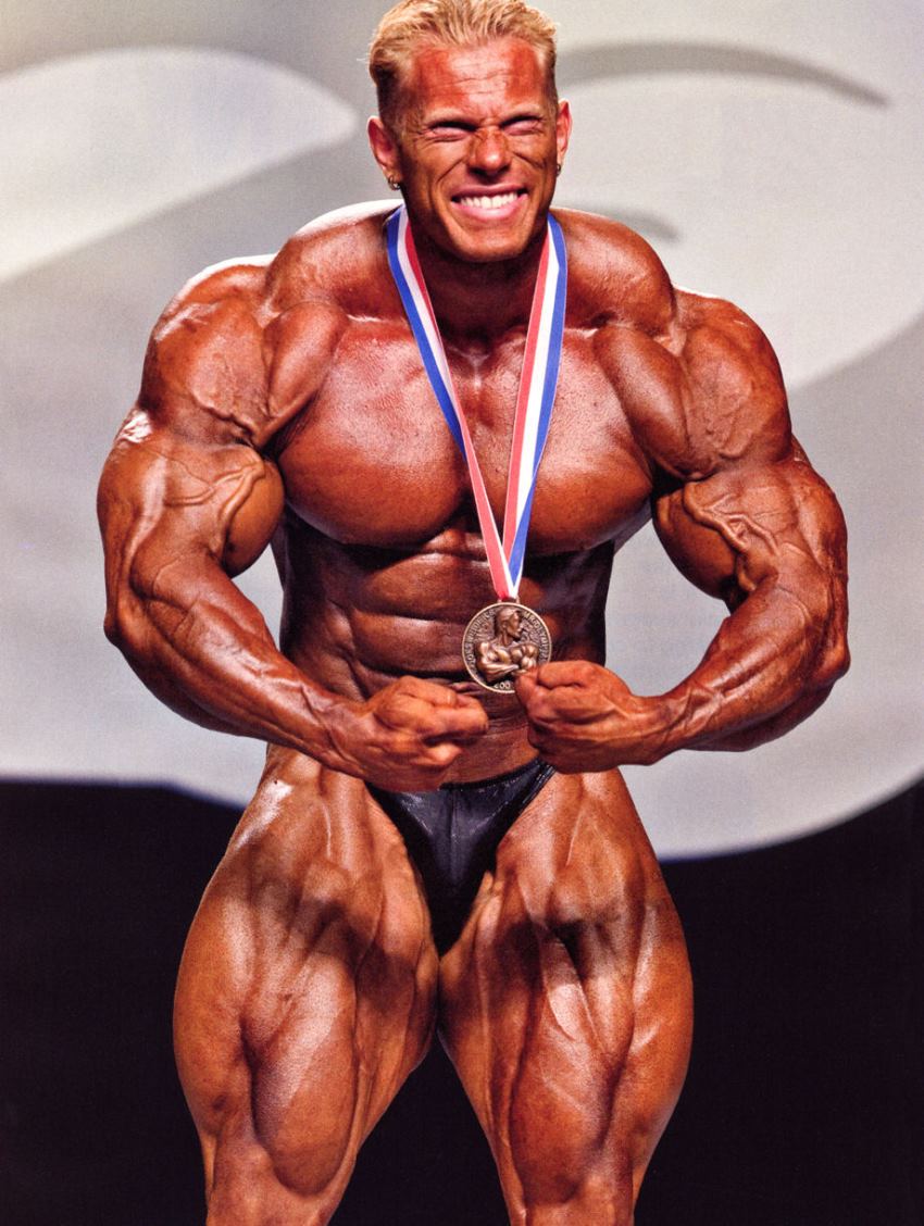 Dennis Wolf flexing on the stage with a medal around his neck