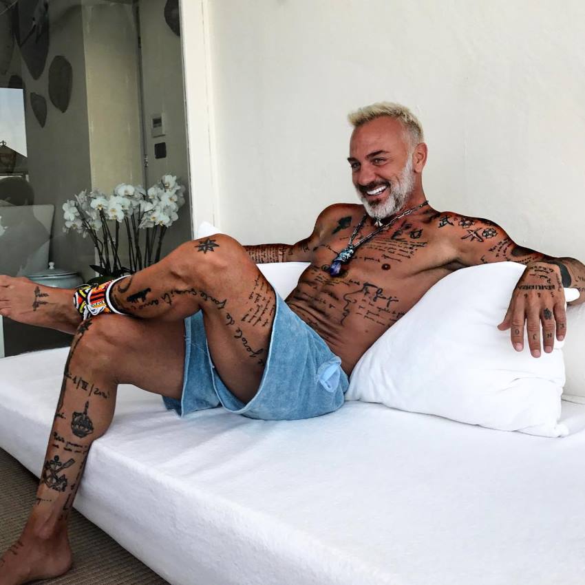 Gianluca Vacchi sitting down on a sofa, smiling, looking lean and happy