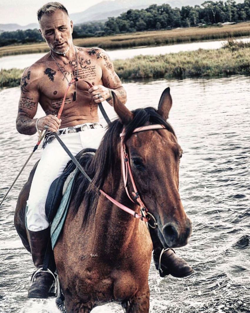 Gianluca Vacchi riding a horse on the lake