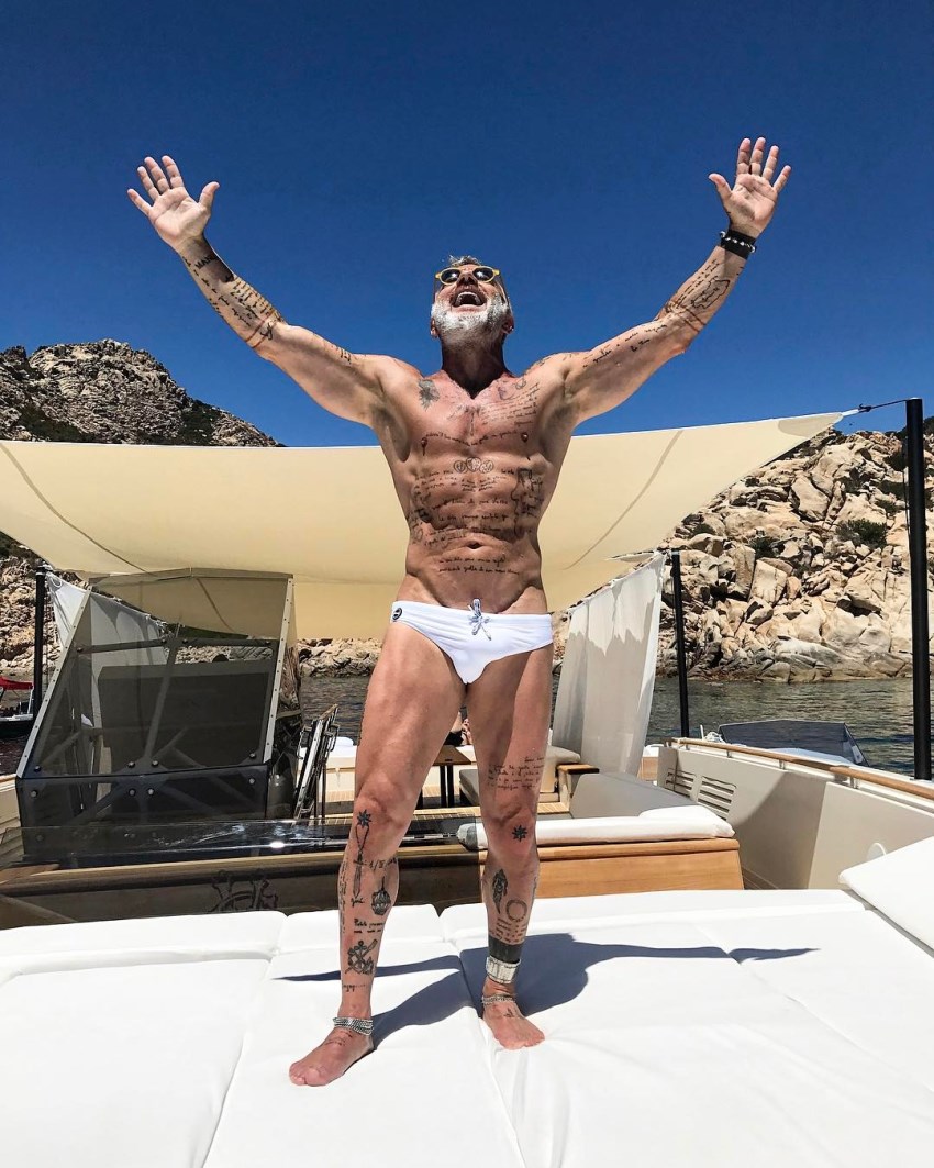 Gianluca Vacchi with his arms spread wide in the air, looking lean and healthy