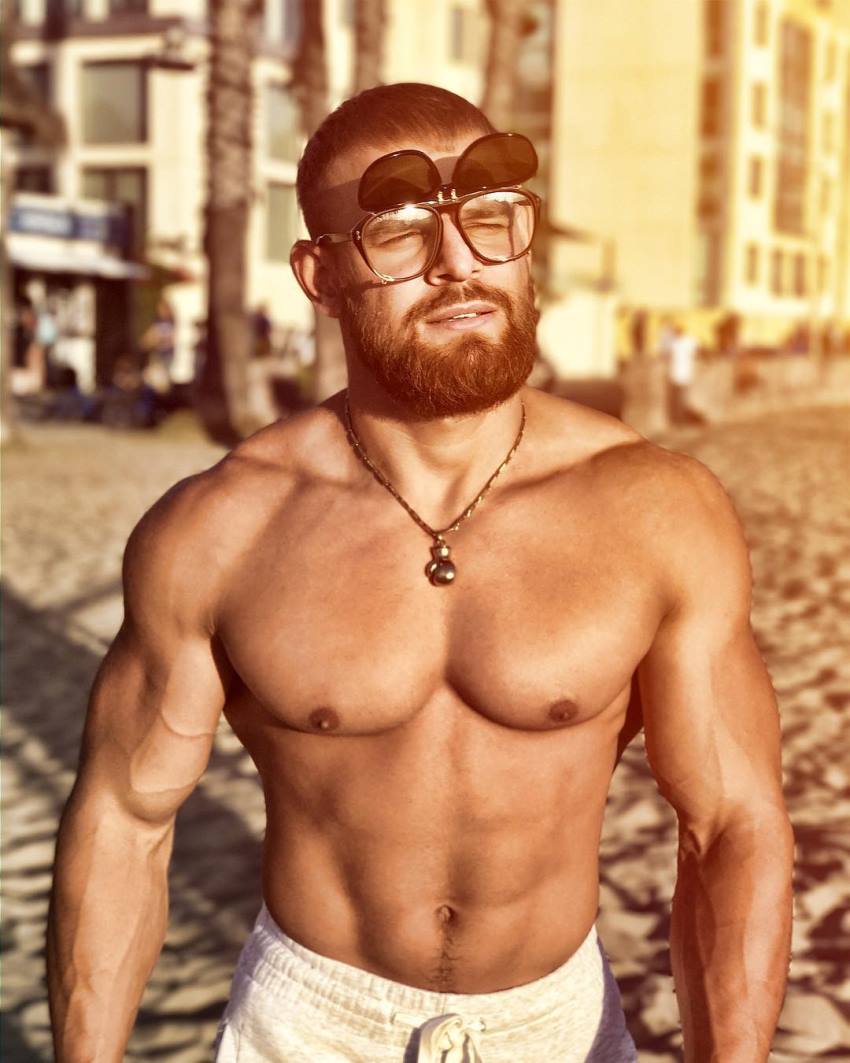 Islam Badurgov walking down the beach shirtless with glasses on, looking fit