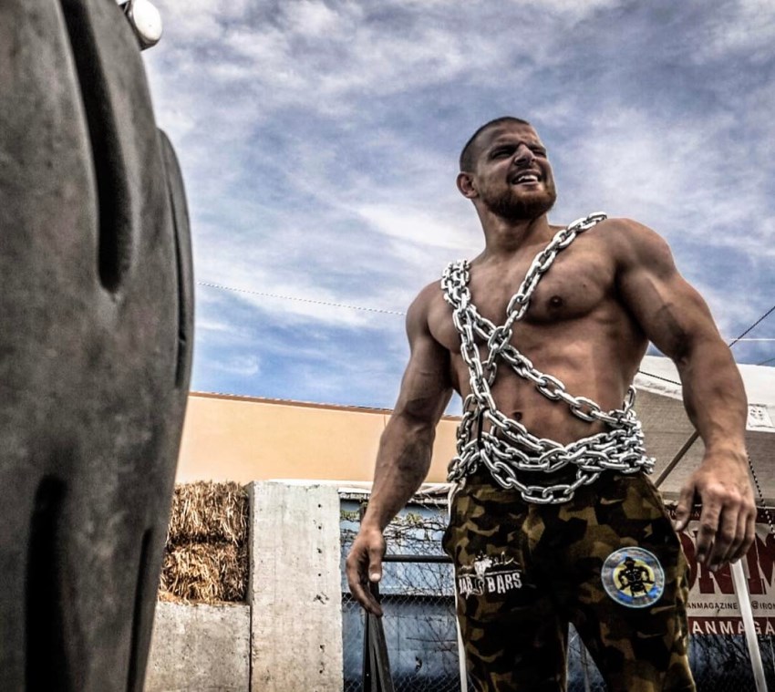 Islam Badurgov standing outdoors with chains around his shirtless body