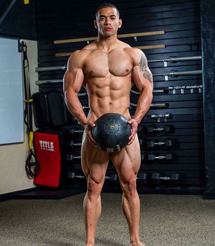 Jamie LeRoyce standing naked, covering his intimate area with medicine ball, looking lean and muscular