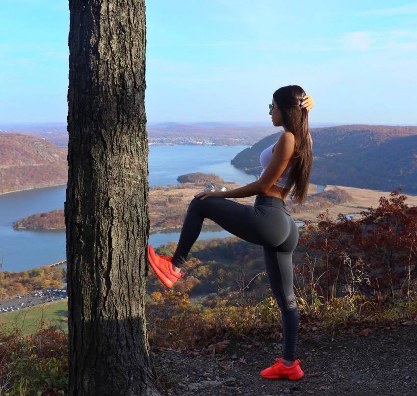 Jen Selter standing on the hill by a tree, showcasting her glutes in black leggings