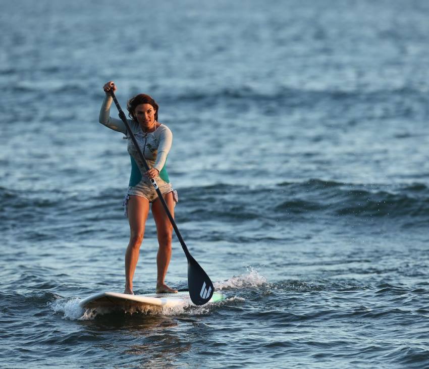 Lauren Abraham paddle-surfing in the sea