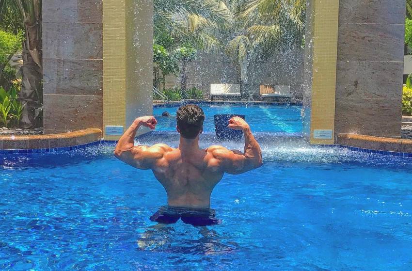 Mohammad Kashanaki doing a back double biceps pose while being shirtless in a pool