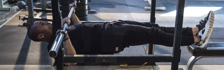 Ryan Tremaine Klarenbach doing an exercise with a barbell on the bench