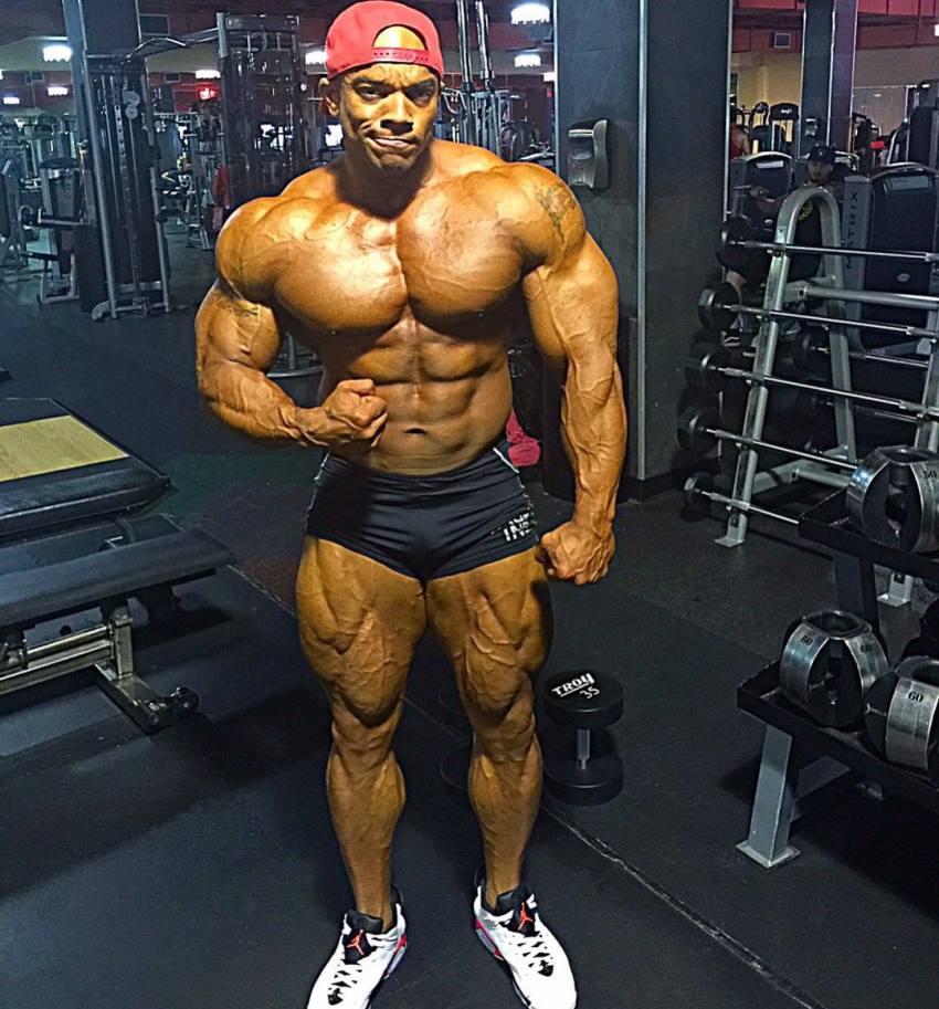 Sergio Oliva Jr posing shirtless in the gym, looking big and ripped