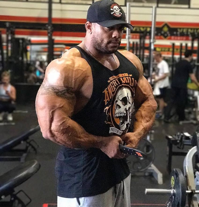 Sergio Oliva Jr flexing his arms in the gym