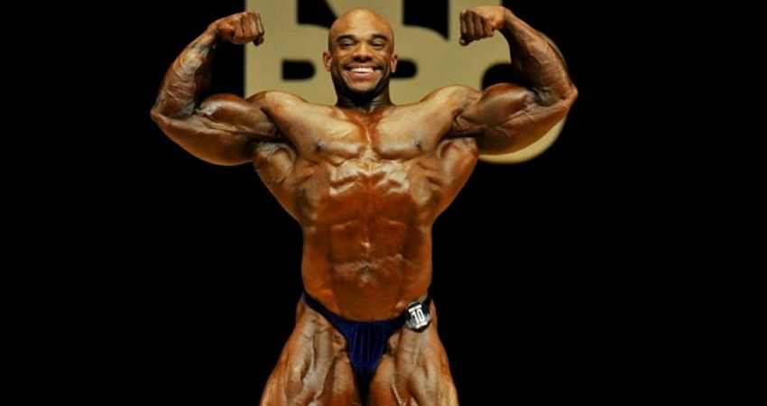 Sergio Oliva Jr hitting a front double biceps pose on the stage