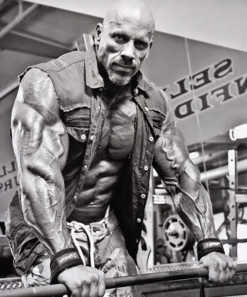 Stan Efferding leaning against an iron bar in the gym, looking ripped and big