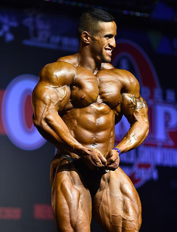 Abdelaziz Jellali in a most muscular pose on the stage in front of the audience