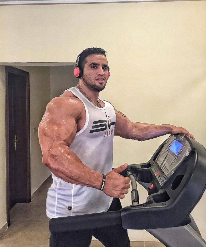 Abdelaziz Jellali doing cardio on a treadmill, his arms looking massive