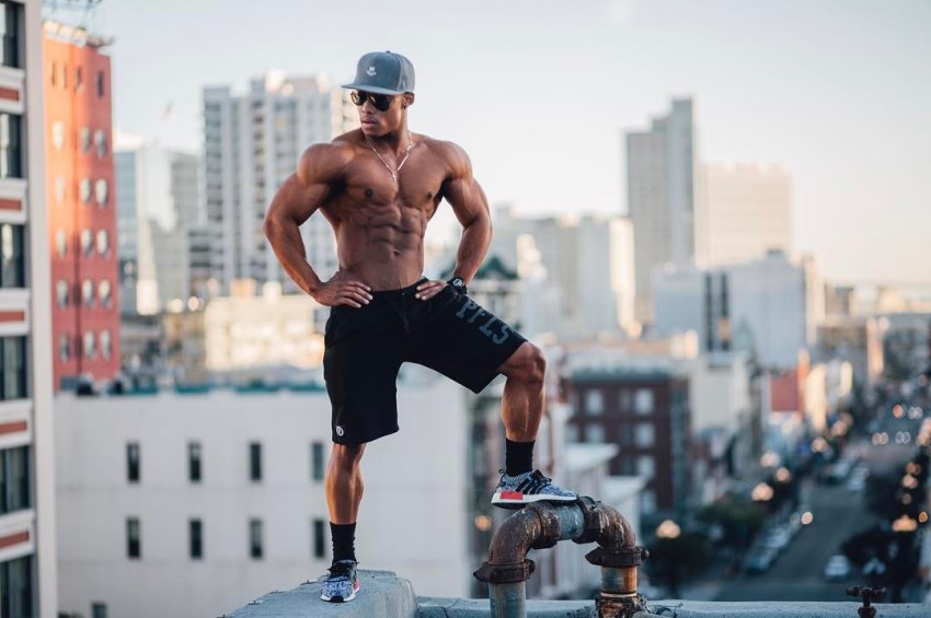 Ahmad DeGuzman standing shirtless on top of a skyscraper