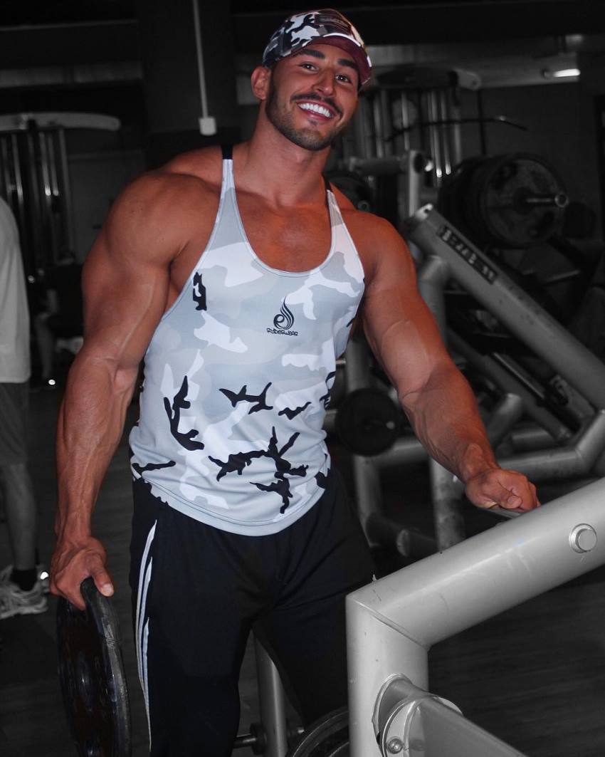 Amin Elkach in the gym in a grey tank top, smiling at the camera