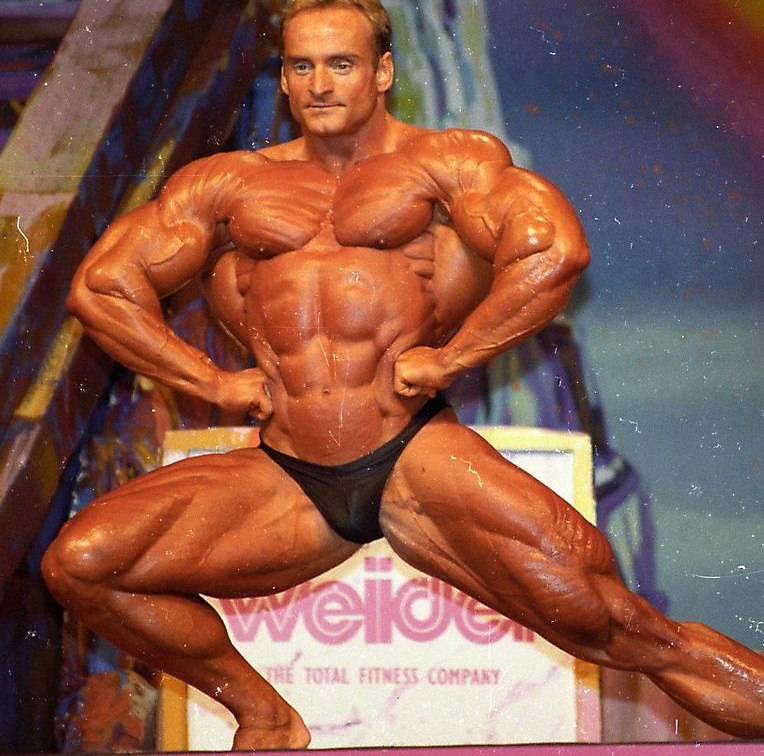 Andreas Munzer spreading his lats wide on the stage, and showcasting his ripped physique