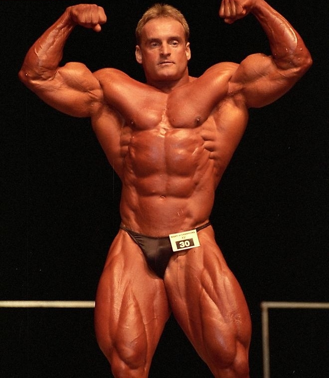 Andreas Munzer doing a front double biceps pose on the stage