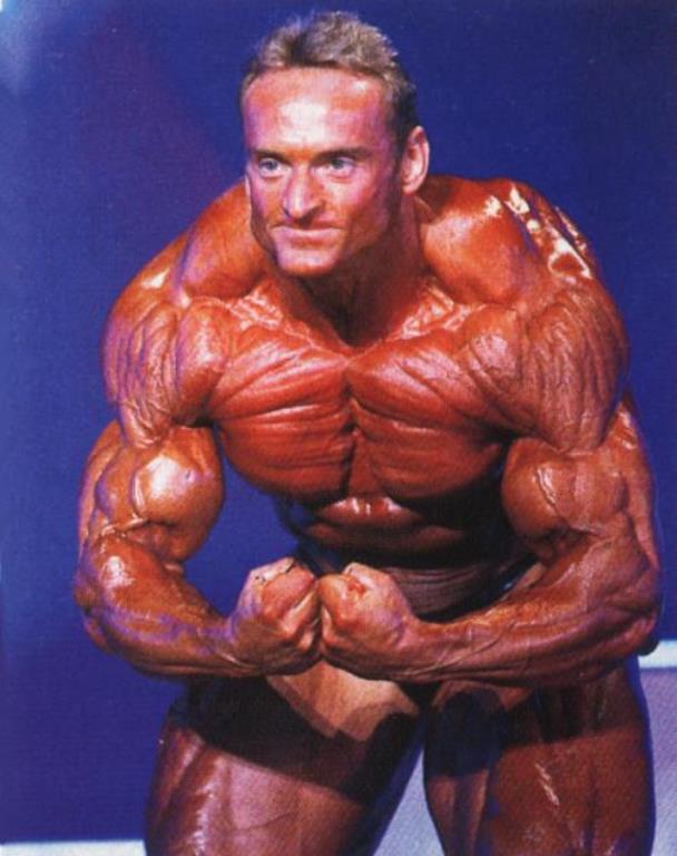Andreas Munzer doing the most muscular pose on the stage, looking incredibly ripped