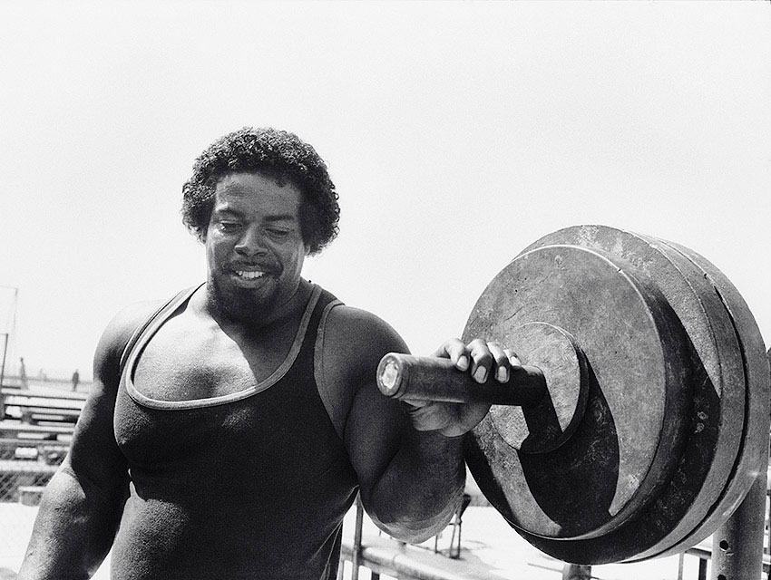 Bill Pettis in his prime, holding onto a barbell for the 1984 Olympics poster.