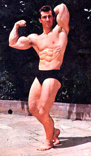 Bob Gajda flexing his biceps and abs outdoors