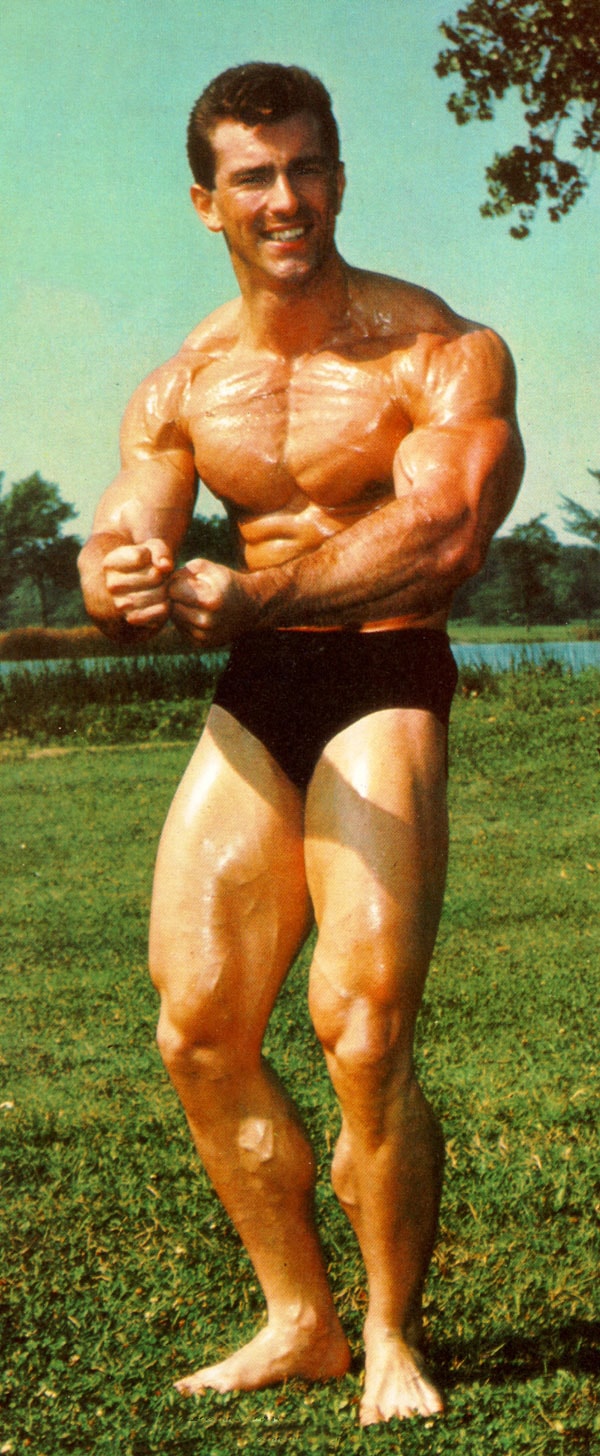 Bob Gajda in a most muscular pose outdoors, standing on the grass, and posing for a photo