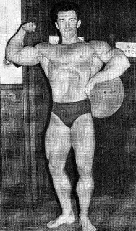 Bob Gajda doing a vacuum pose and one-arm biceps flex on the stage