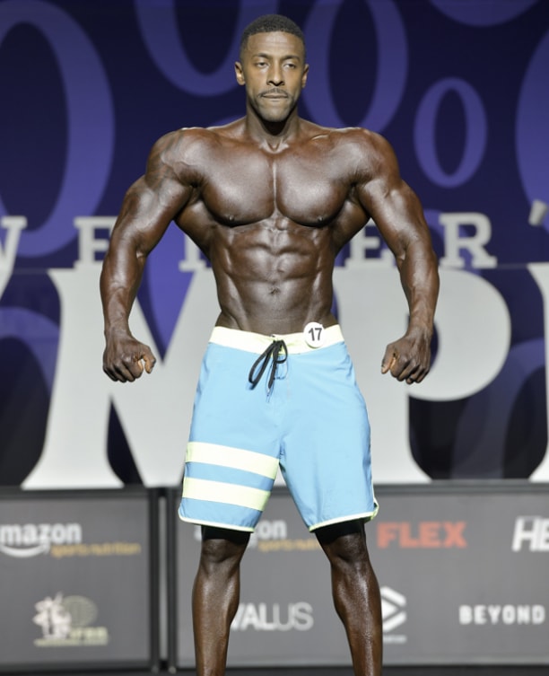 Coty Hart posing on the stage spreading his lats wide