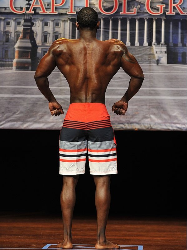 Coty Hart showing his back on the men's physique stage