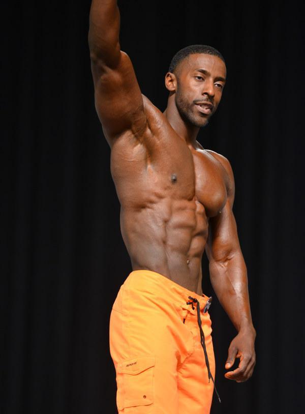 Coty Hart waving at the audience showing his ripped abs on the stage