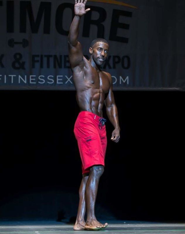 Coty Hart standing on the stage in red shorts waving at the audience