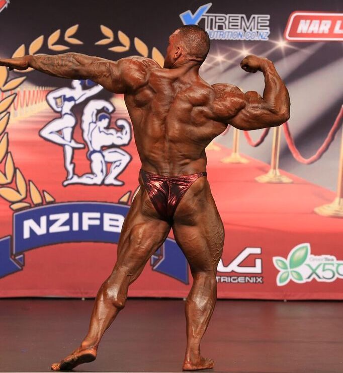Darryn Onekawa flexing and showing his back to the judges on the stage