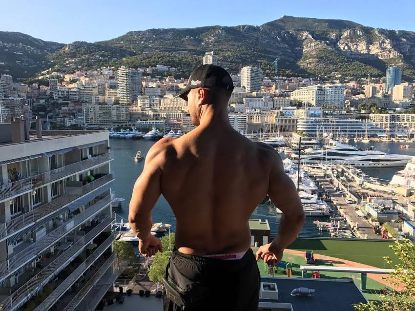 Emil Goliath overlooking a city from skyscraper rooftop, showcasting his lean back