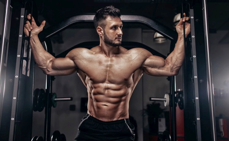 Emil Goliath posing shirtless in the gym, looking ripped