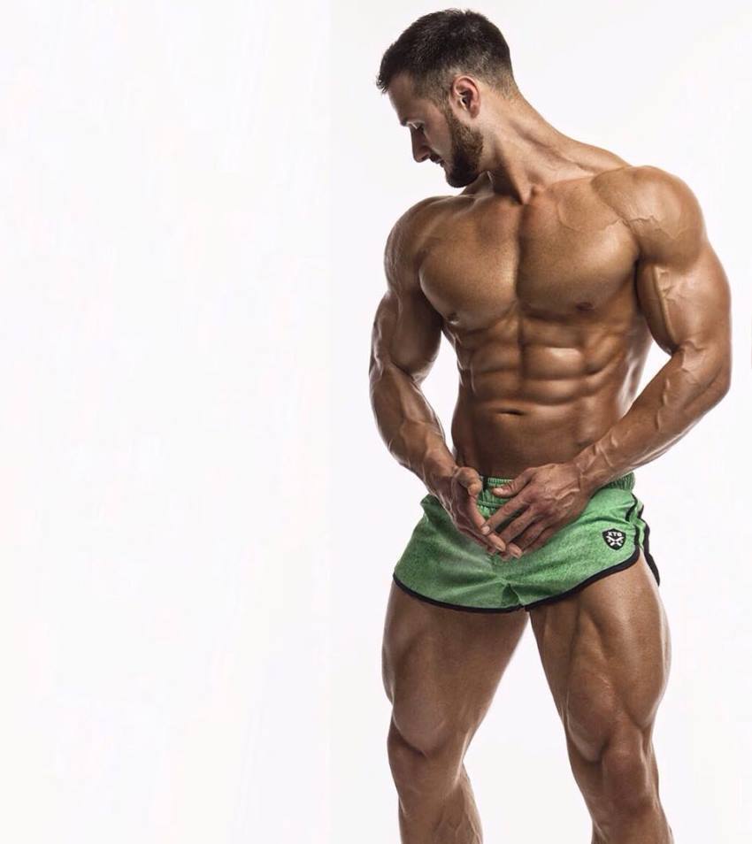 Emil Goliath posing for a photoshoot in green shorts, looking ripped and muscular