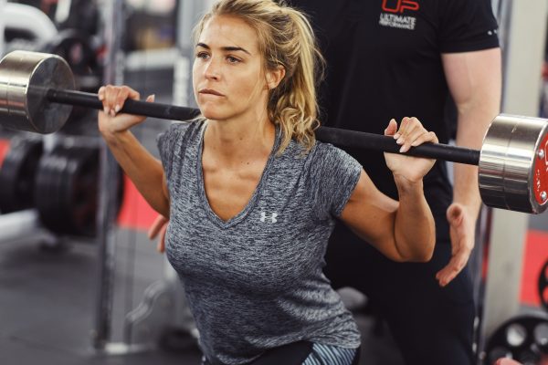 Gemma Atkinson doing squats with her personal trainer behind her