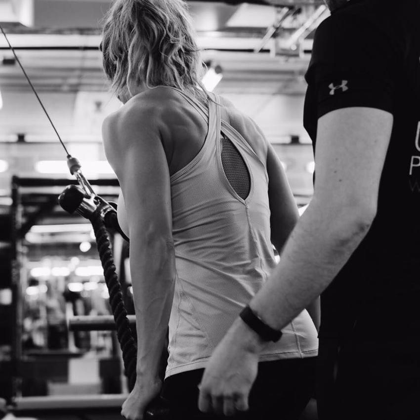 Gemma Atkinson doing cable exercises alongside her trainer