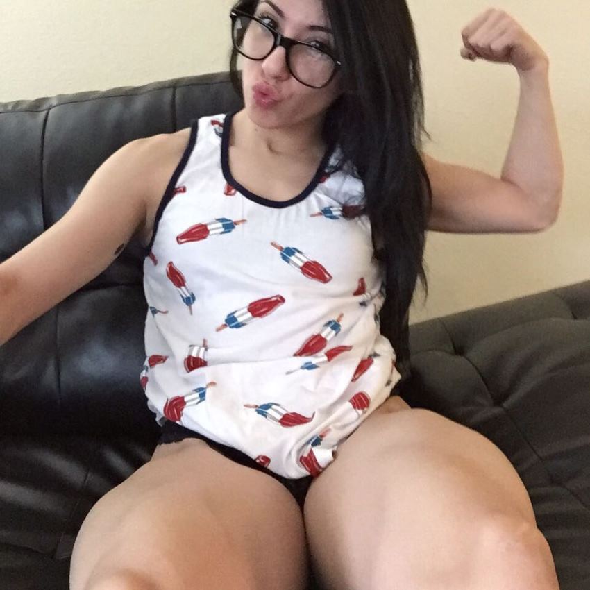 Jennifer Sue taking a selfie of herself flexing her legs and biceps