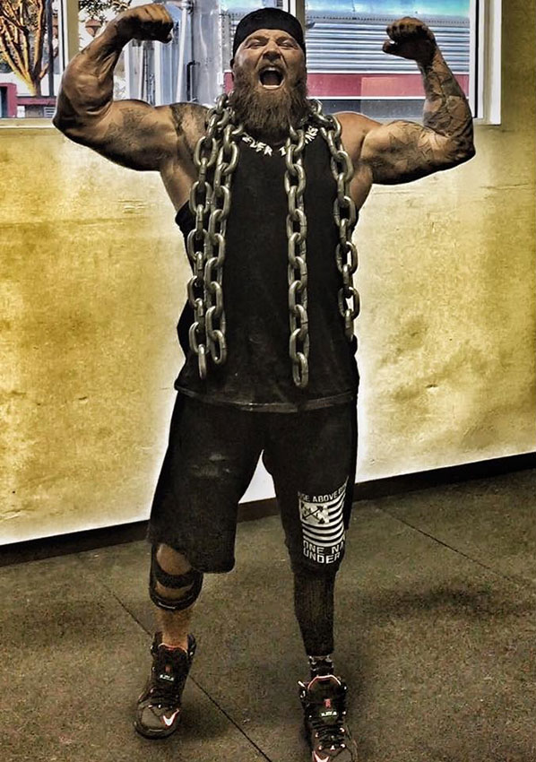 KC Mitchell flexing his biceps with chains around his neck.