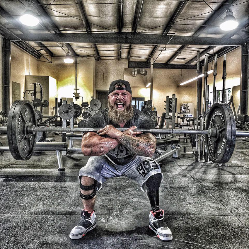 KC Mitchell in the gym holding a barbell with crossed arms.