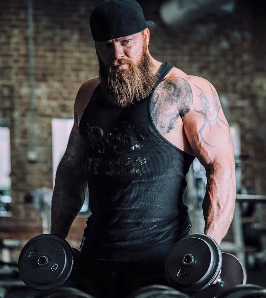 KC Mitchell holding two dumbbells in a photo shoot.