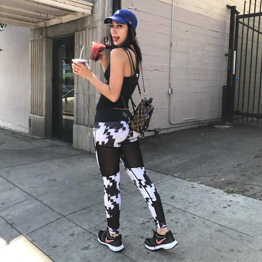 Lexy Panterra showing her legs and glutes in black and white leggins whilst drinking a juice
